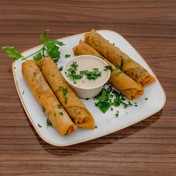 Golden-brown spring rolls with a side of creamy dipping sauce, garnished with fresh parsley on a white plate.