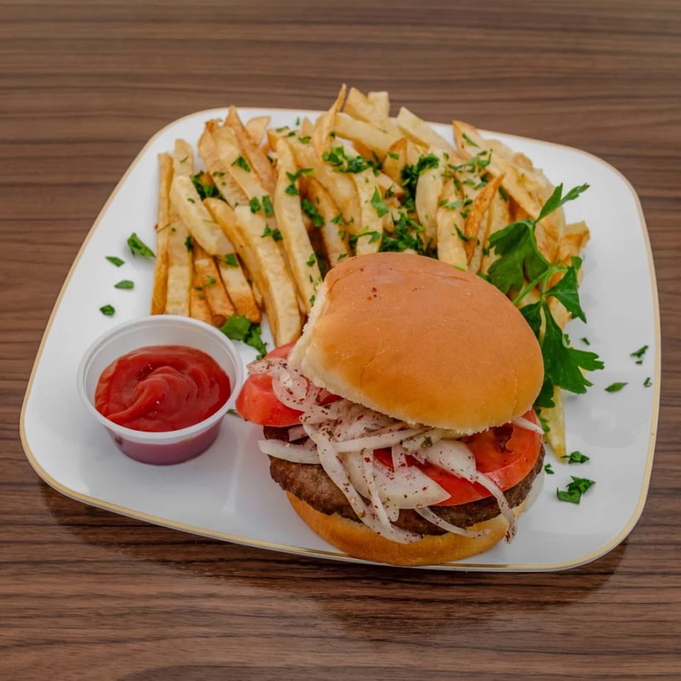 A hamburger with tomatoes and onions, served with french fries and a side of ketchup.