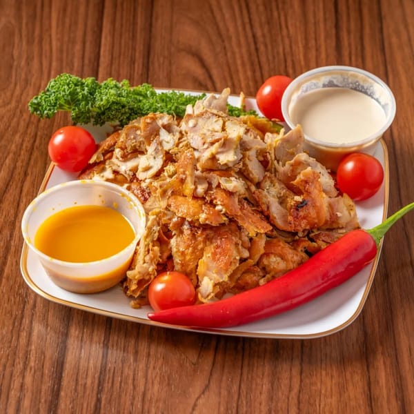 Chicken shawarma plate with kale, cherry tomatoes, red chili, and two dipping sauces.