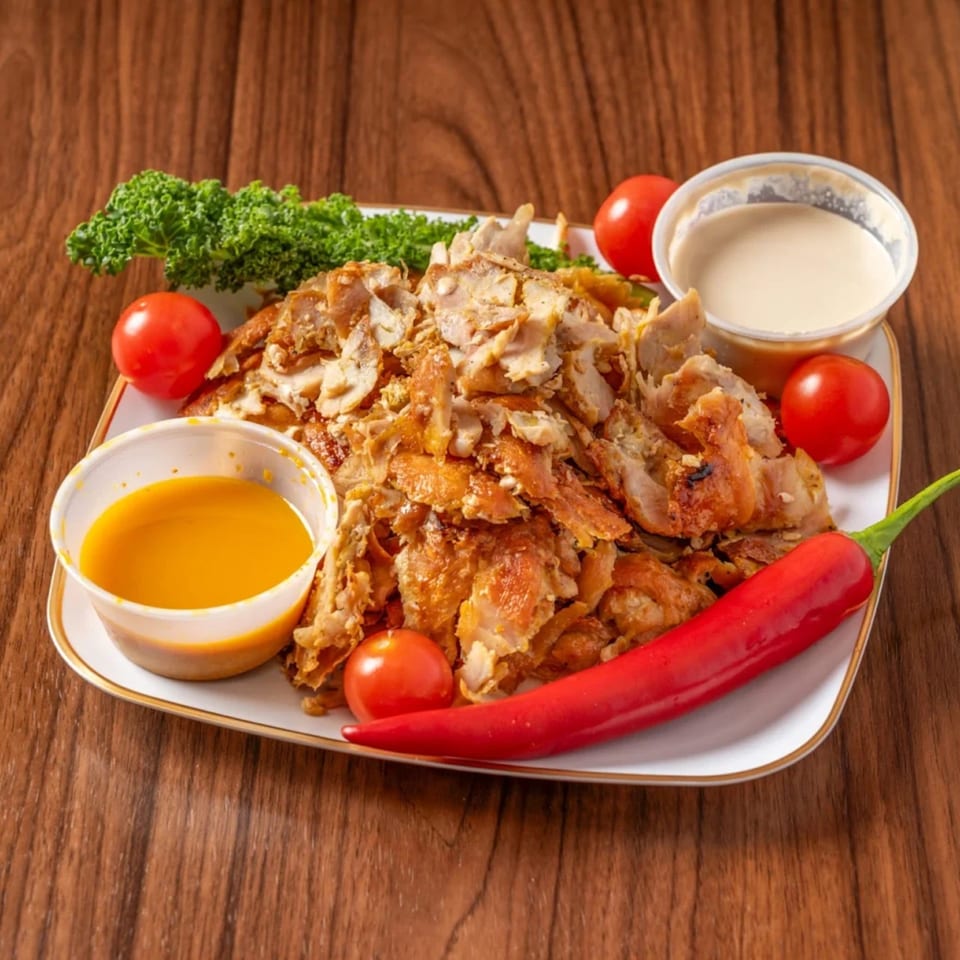 Chicken shawarma plate with kale, cherry tomatoes, red chili, and two dipping sauces.